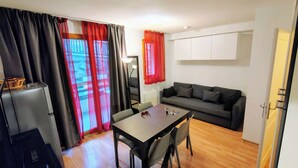 Un espace de vie compact comprenant un canapé, une table à manger et un réfrigérateur.