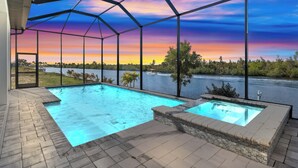 En swimmingpool med utsikt över en flod och solnedgången.
