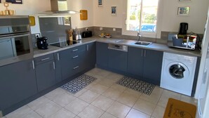Una cocina moderna con armarios grises, electrodomésticos de acero inoxidable, un horno empotrado y una lavadora.