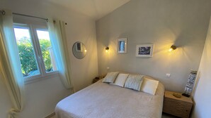 Un dormitorio con una cama grande, dos mesitas de noche, una ventana con cortinas y luces fijadas a la pared.