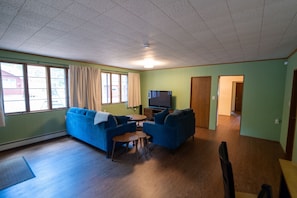 A living room with a blue sofa set, a television, and a dining table.