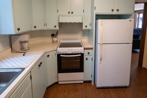 A kitchen with white cabinets, a white refrigerator, a stove, and a sink.