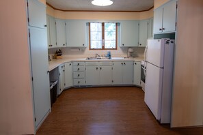 A kitchen with light blue cabinets, a wooden floor, and a window above the sink.