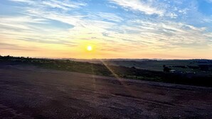 A sunset over a flat landscape with a dirt road leading towards the horizon.