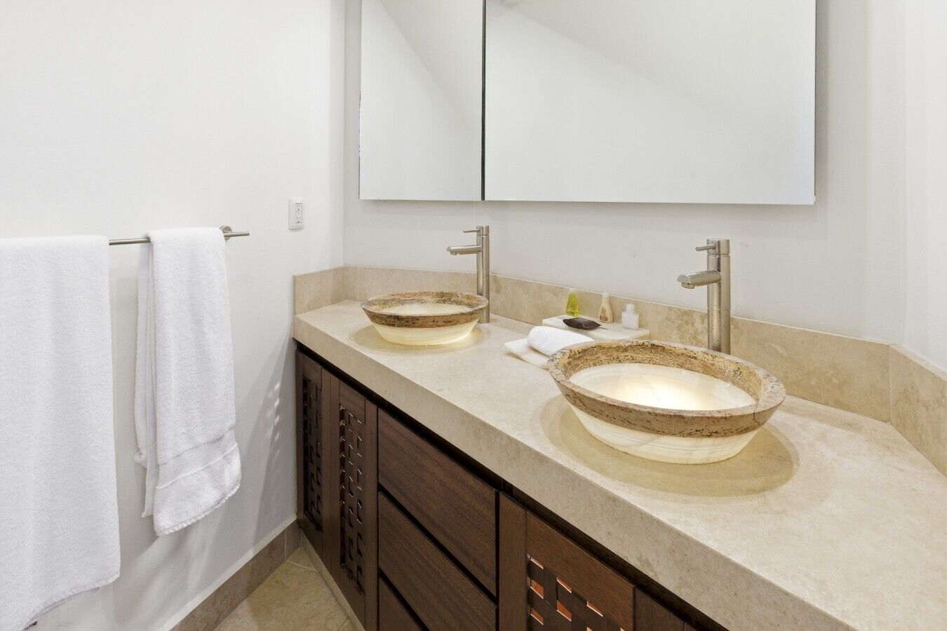 A bathroom with two vessel sinks, a mirror, and a towel rack.