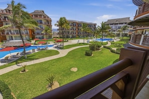 A resort with multiple swimming pools, palm trees, and a well-maintained lawn.