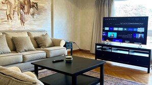 Ein Wohnzimmer mit einer Couch, einem Couchtisch und einem Flachbildfernseher.