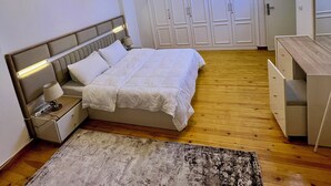 Ein Schlafzimmer mit Bett, Nachttisch, Lampe, Kleiderschrank und Schreibtisch.