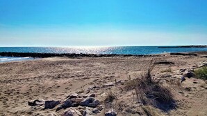 En sandstrand med en klippefyldt kystlinje og en klar blå himmel.