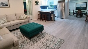 Een moderne woonkamer met een bank, een poef en een kamerkleed met dessin.