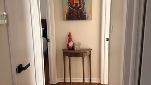 Um corredor com piso de madeira, paredes brancas e um quadro de um urso na parede.