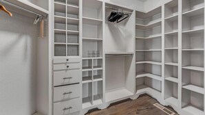 Ein begehbarer Kleiderschrank mit mehreren Regalen, Schubladen und Platz zum Aufhängen.