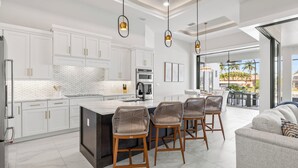 Une cuisine moderne avec des meubles blancs, un îlot central et des tabourets de bar.