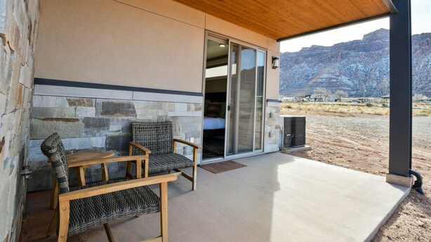 A covered patio with stone walls, a wooden ceiling, and a view of a mountainous landscape. - C2-C3 Combo - Moab Sage Creek Resort - Heated Pool (Moab)