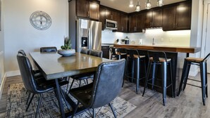 A modern kitchen with dark wood cabinets, stainless steel appliances, and a central island with bar stools. - C2-C3 Combo - Moab Sage Creek Resort - Heated Pool (Moab)