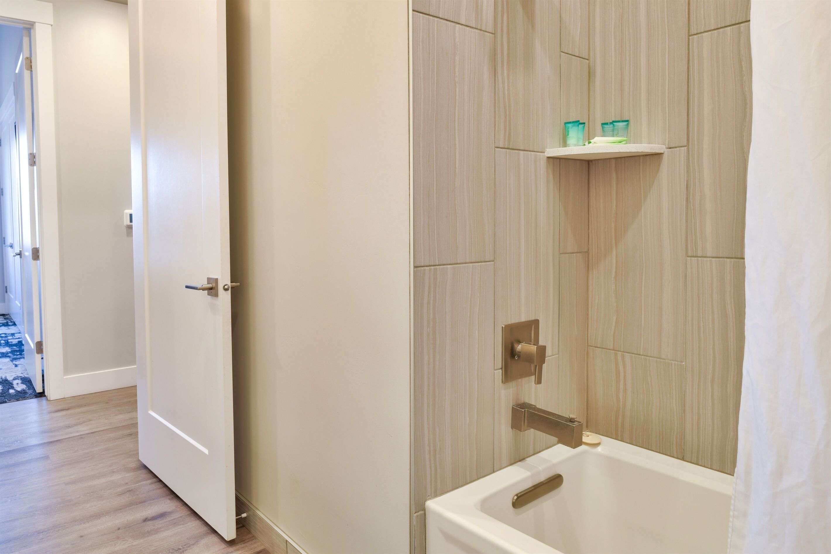 Un baño con bañera, ducha y estante con artículos de aseo.