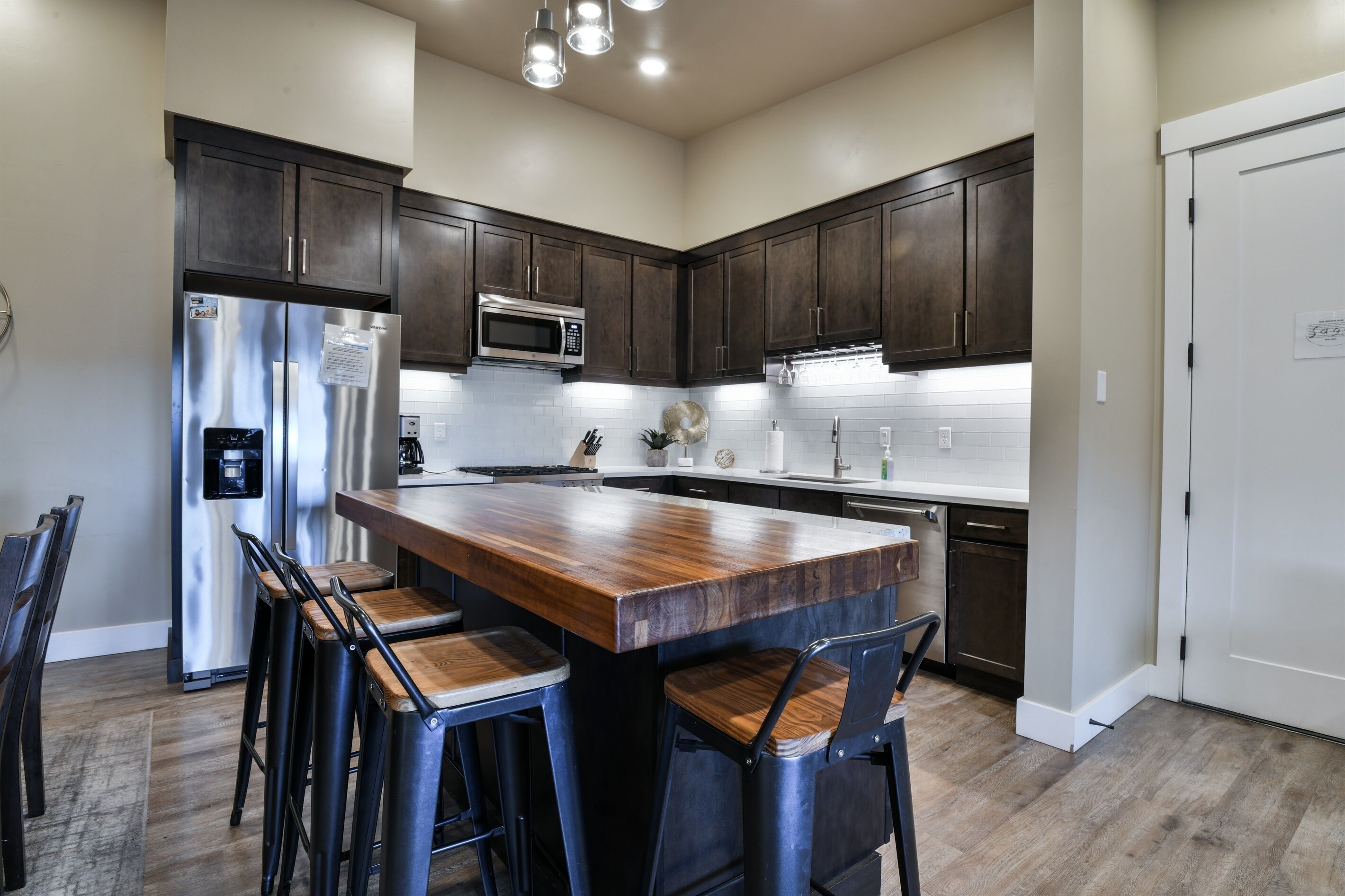 A modern kitchen with dark wood cabinets, stainless steel appliances, and a central island with bar stools.