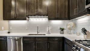 Een moderne keuken met donker houten kastjes, roestvrijstalen apparatuur en een witte betegelde spatwand.