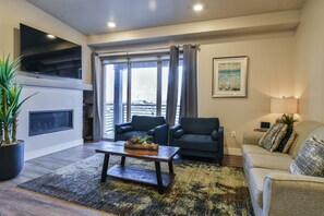 A modern living room with a fireplace, two sofas, a coffee table, and a large window with curtains. - C9 and C12 Combo - Sage Creek - Elevated Pool View (Moab)