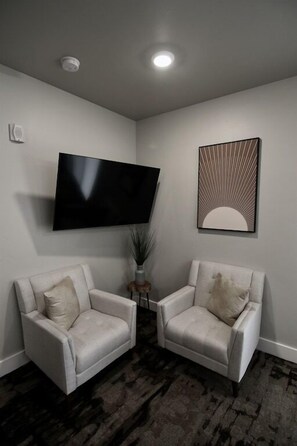 A modern living room with two white armchairs, a flat-screen TV, and a decorative wall piece. - D1 and D4 Combo Unit - Sage Creek Resort Moab (Moab)