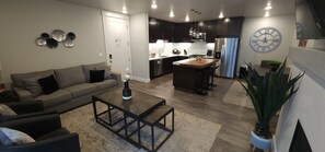 A modern living room with a sofa, coffee table, and a kitchen area with a refrigerator, microwave, and sink. - D1 and D4 Combo Unit - Sage Creek Resort Moab (Moab)