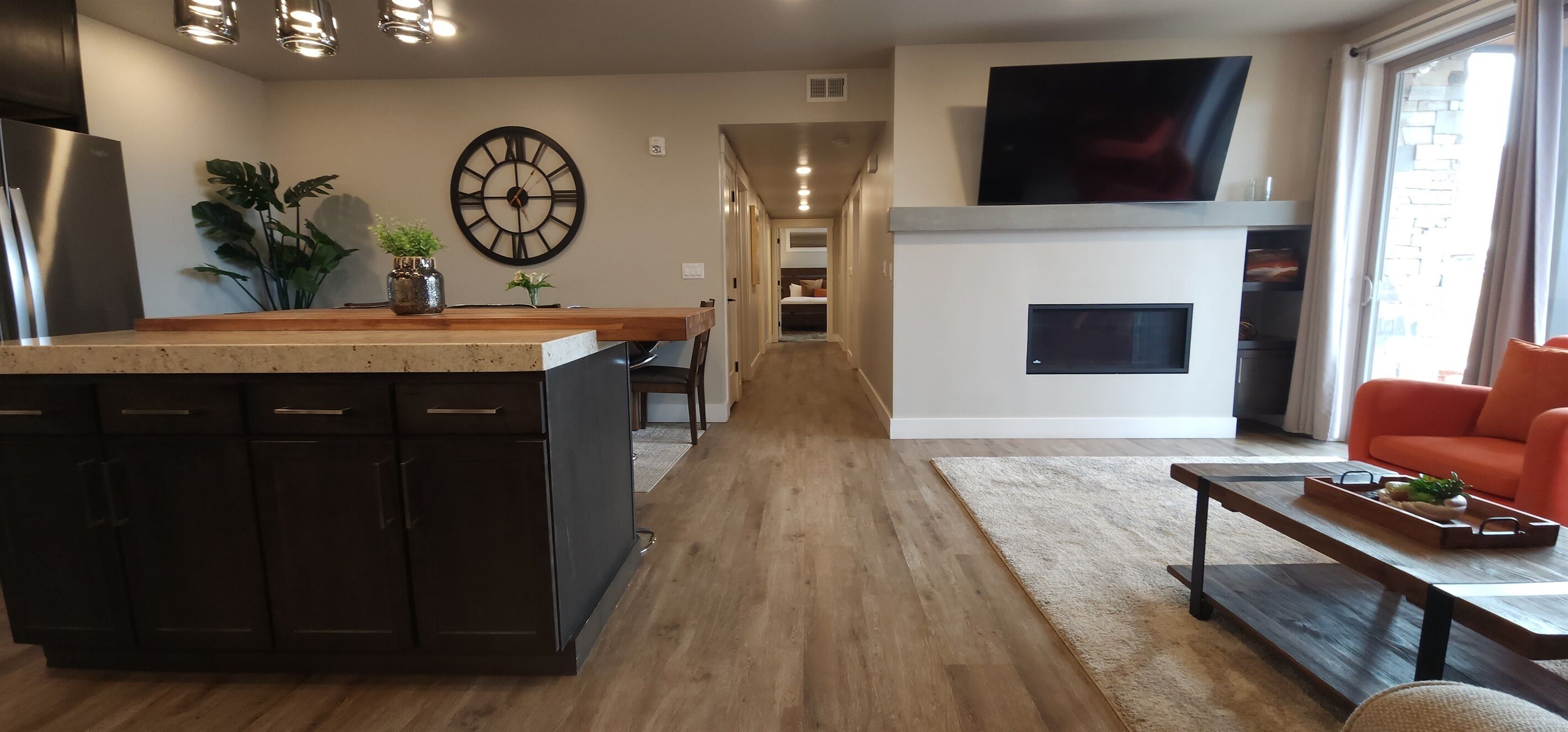 Een moderne keuken met een centraal eiland, een eetgedeelte met een lange tafel, een woonkamer met een bank en een open haard.