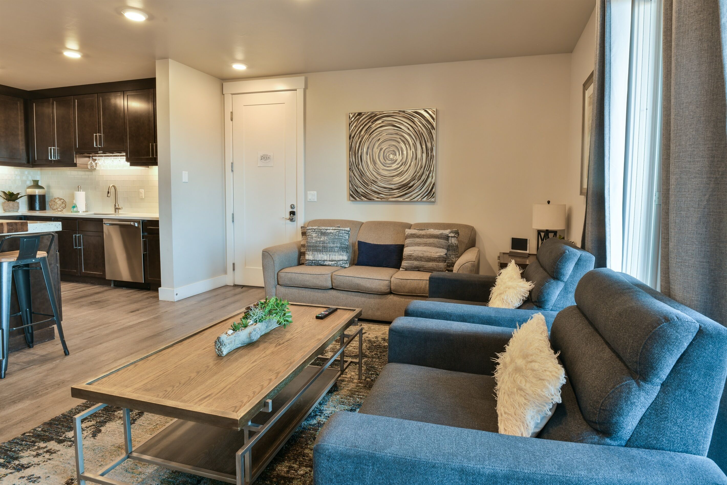 A modern living room with a sofa, coffee table, and a kitchen area in the background.