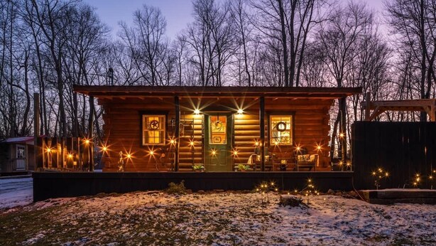 A wooden cabin with a porch, a green door, and windows.