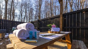 Ein Picknicktisch aus Holz mit Handtüchern, einer Flasche und einer Karte in einem Garten.