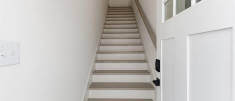 Una escalera con paredes blancas y una puerta al final.