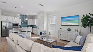 Ein modernes Wohnzimmer mit einer Couch, einem Couchtisch und einem Fernseher, der eine Strand Szene zeigt.