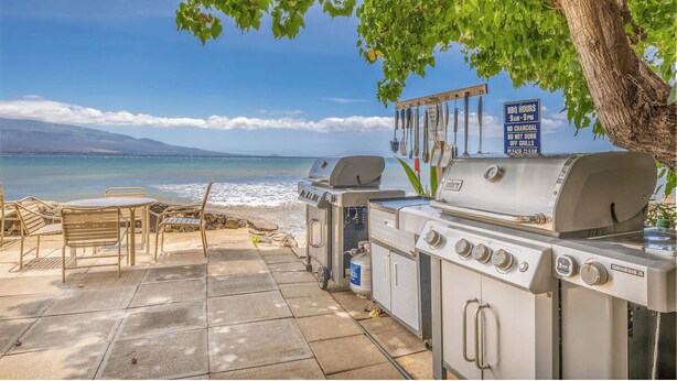 Un coin barbecue aménagé avec une vue sur l’océan et les montagnes en arrière-plan.