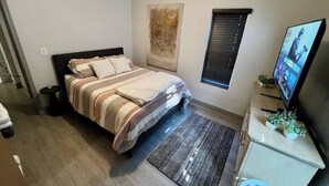 A bedroom with a bed, a television, a small desk, and a window with blinds. - Beautiful Apartment In Downtown Baltimore (Baltimore)