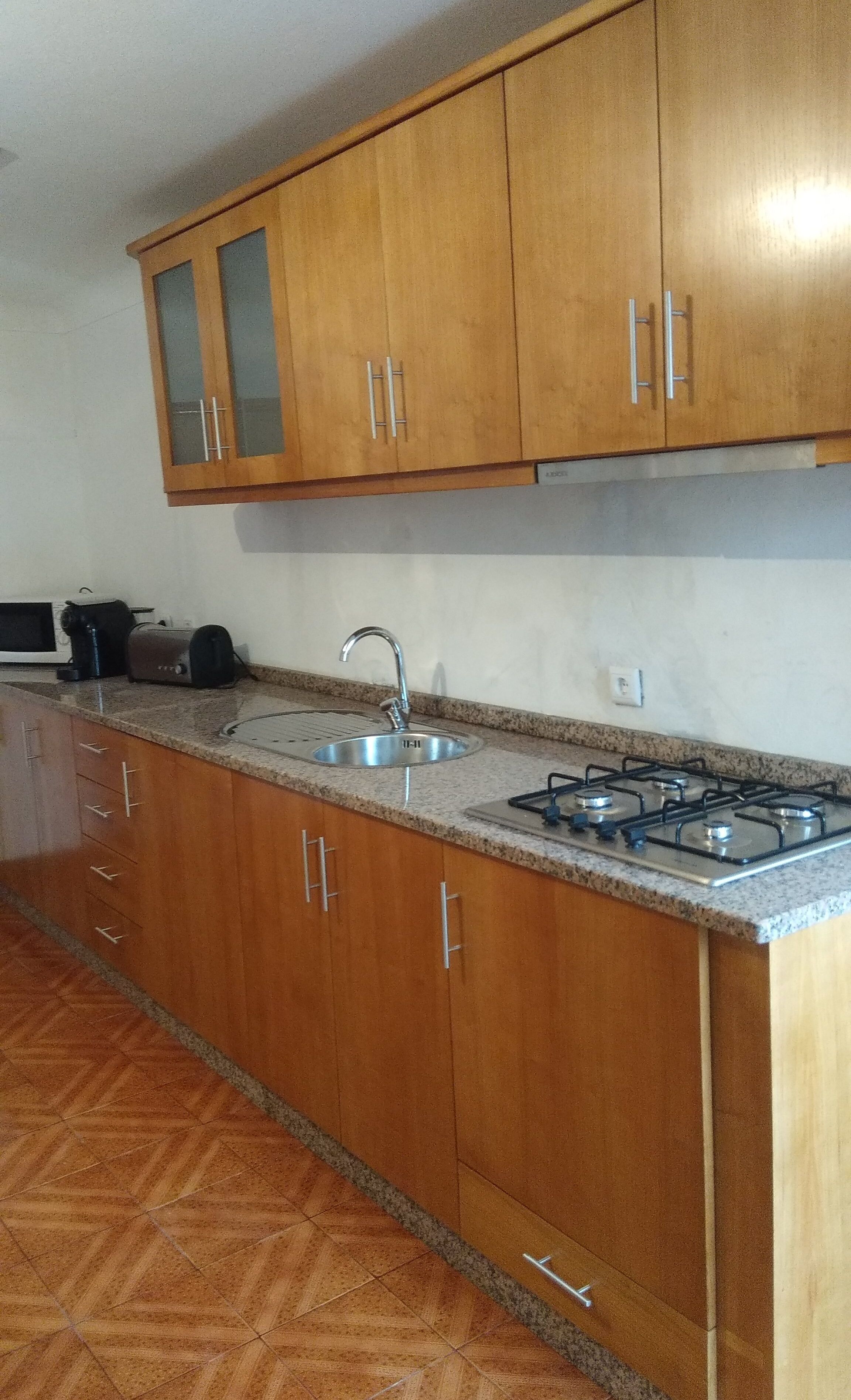 A kitchen with wooden cabinets, a stainless steel sink, a gas stove, and a microwave.