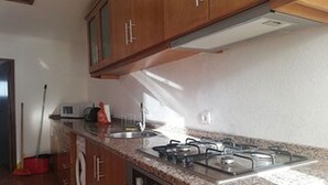 Une cuisine avec des meubles en bois, une cuisinière à gaz et un évier en acier inoxydable.