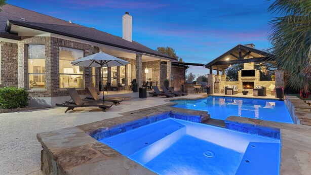 A pool area with a stone deck, lounge chairs, and a covered seating area with a fireplace. - Weekday deals Pool King Bed Giant games Single level Space Firepit Min DT Austin (Austin)