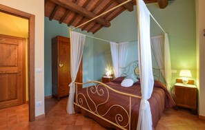 Un letto a baldacchino con tenda, una testiera, un comodino con una lampada e un armadio in legno.