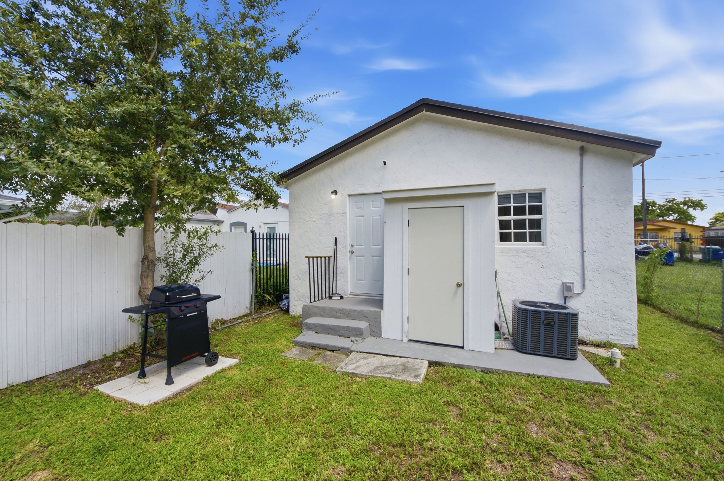 A small, single-story building with a white exterior, a front door, and a small porch.