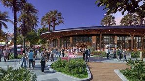 A modern building with a curved roof, surrounded by palm trees and a crowd of people. - La Orquidia (Miami)