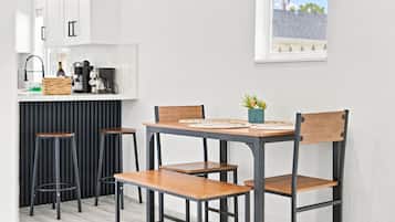Cocina compacta con comedor, que incluye una mesa central con sillas, una cafetera y una pequeña planta en maceta.