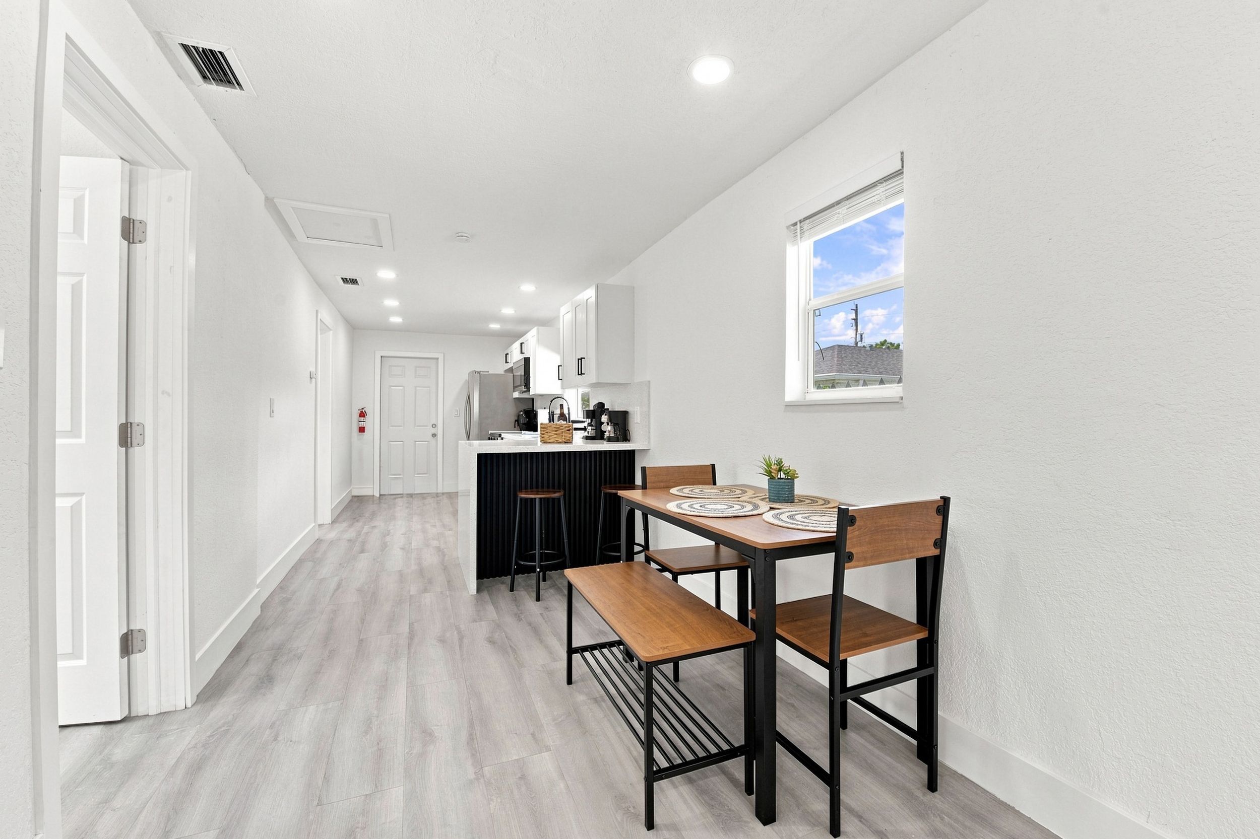 A narrow hallway leading to a kitchen with a dining area.