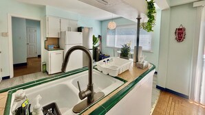A modern kitchen with a stainless steel sink, white cabinets, and a green countertop. - Charming Bright 3BR House - Upper Level Suite (Burnaby)