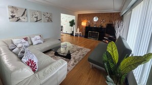 A modern living room with a sofa, coffee table, and a fireplace. - Charming Bright 3BR House - Upper Level Suite (Burnaby)