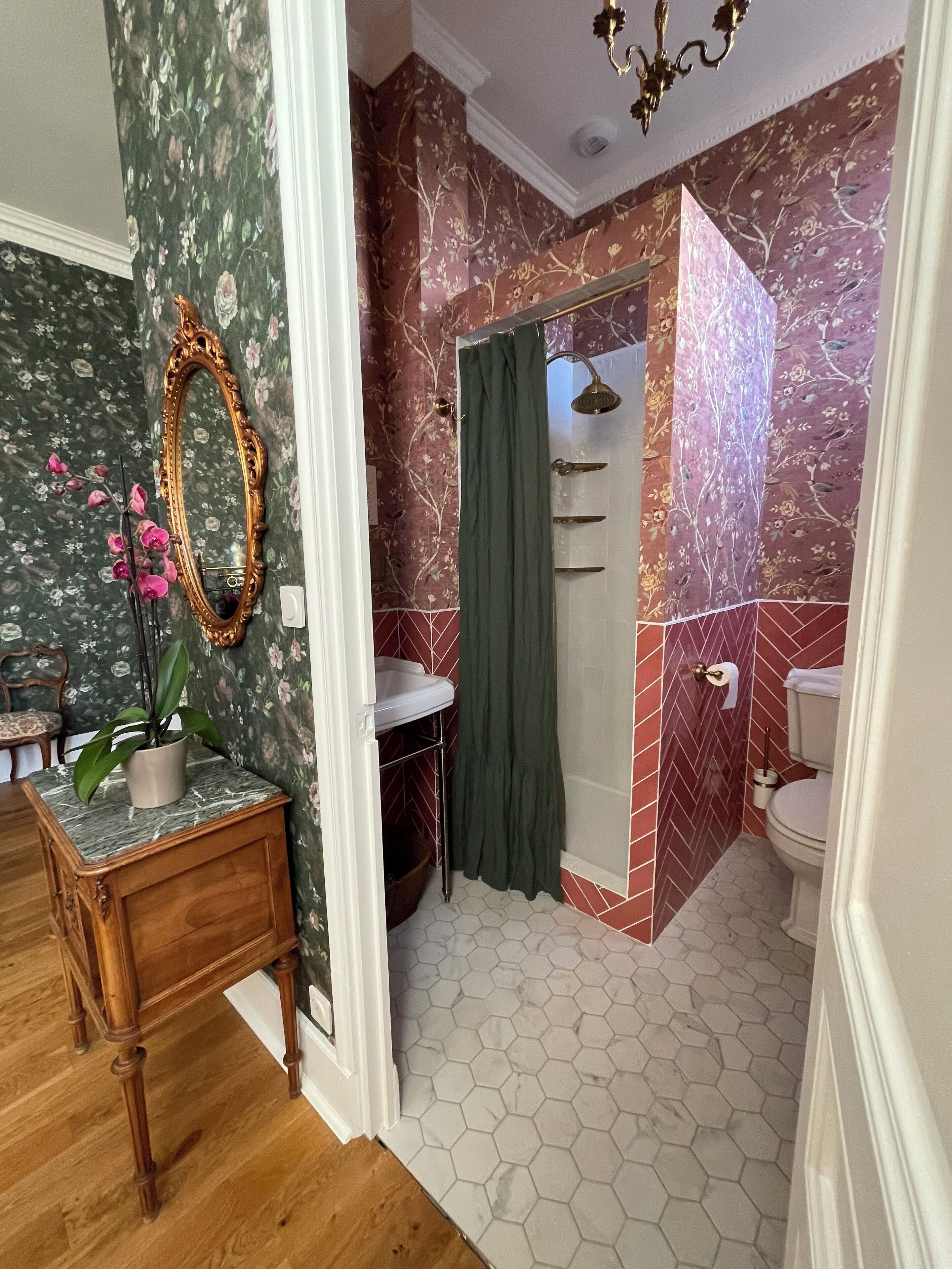 A bathroom with a marble floor, a shower with a green curtain, and a toilet.