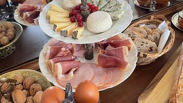 A buffet table with various food items including cheeses, meats, and bread.