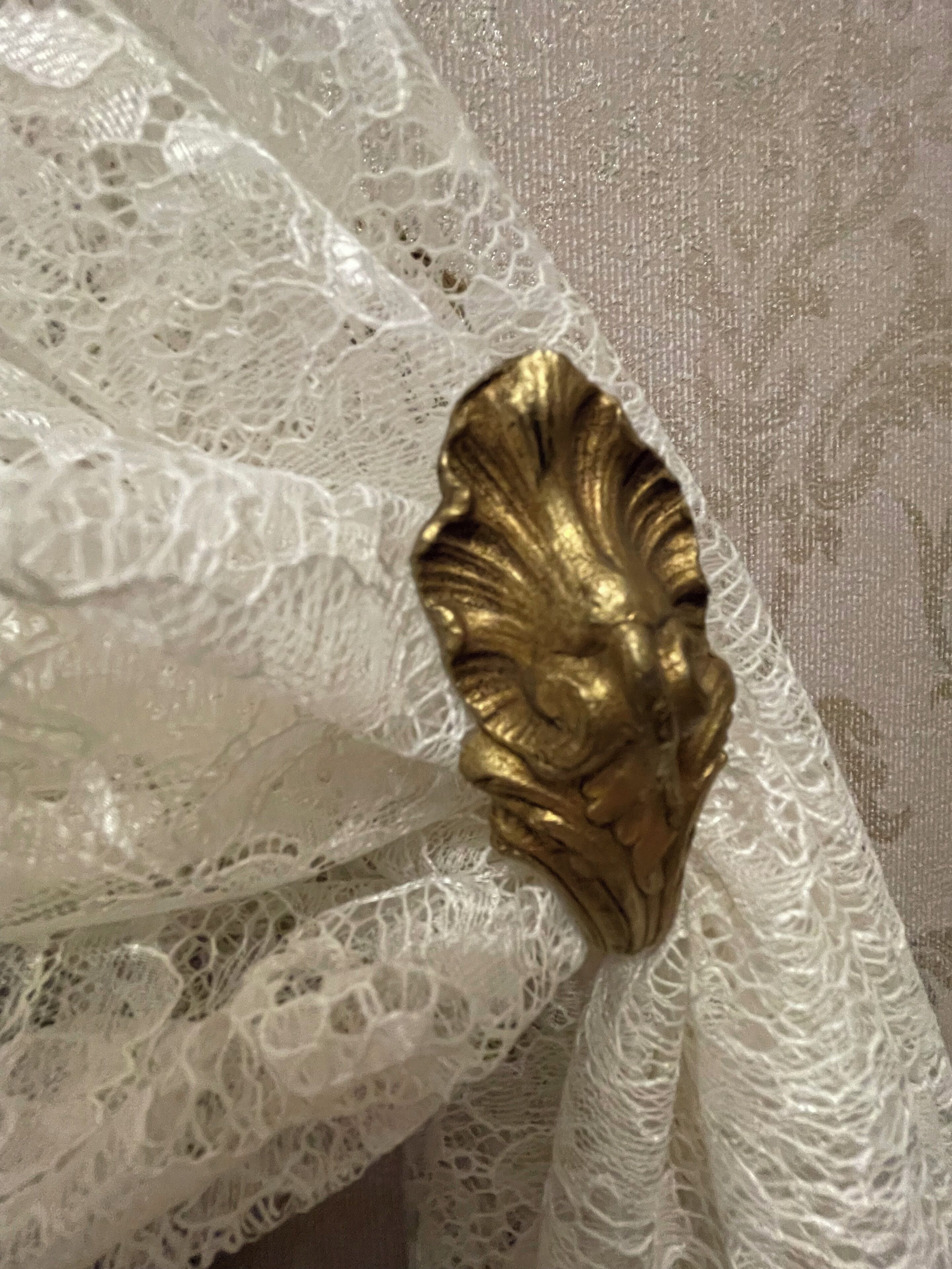 A close-up of a white lace fabric with a gold decorative element.