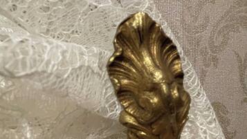 A close-up of a white lace fabric with a gold decorative element.