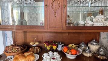 Een houten buffetkast met glazen deuren, gevuld met servies en glaswerk.