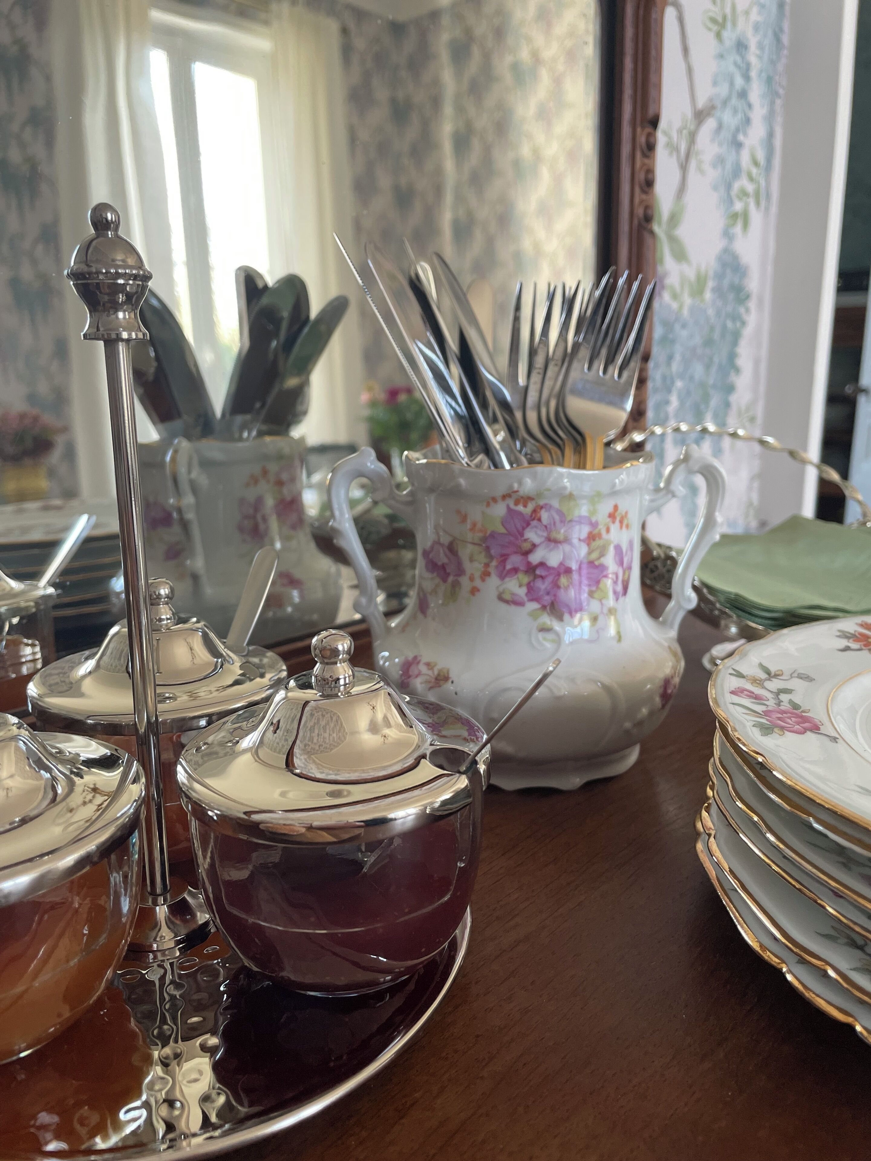 A table set with silverware, teapots, and plates.