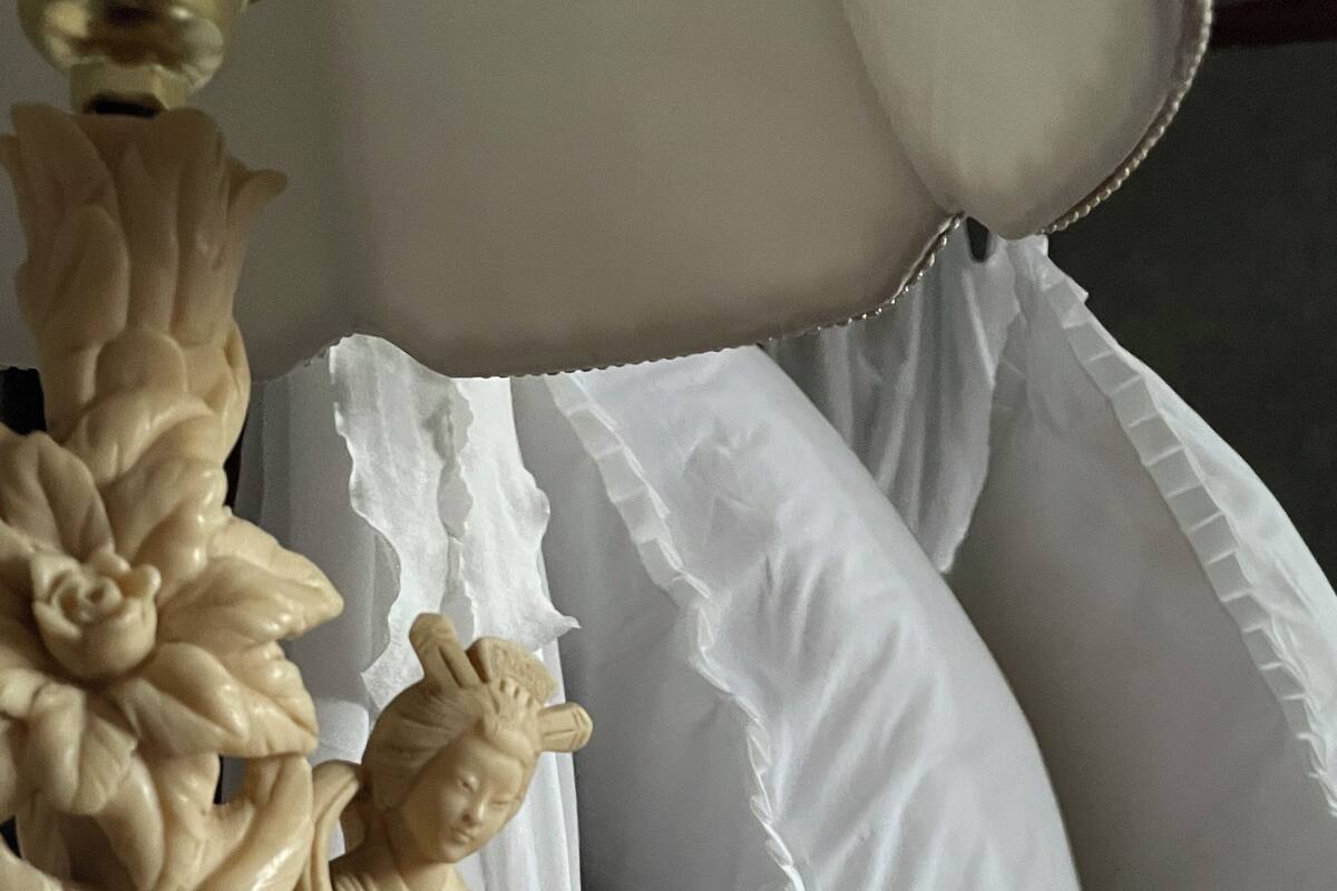 Una cama con almohadas blancas y un cabecero decorativo tallado.